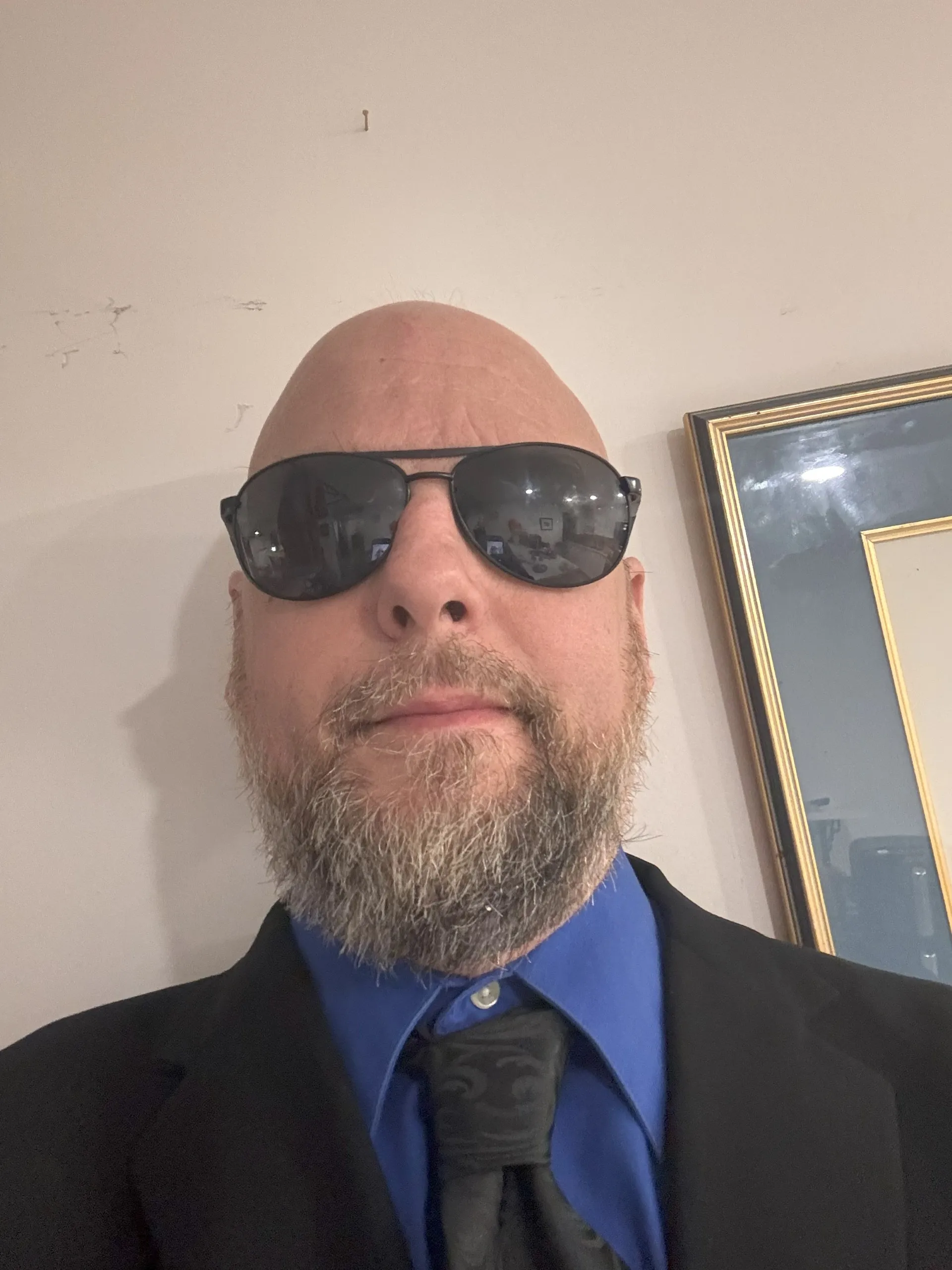 Joel Dazé describes himself as a middle aged man of white colour. He is wearing a dark grey suit jacket along with a blue…